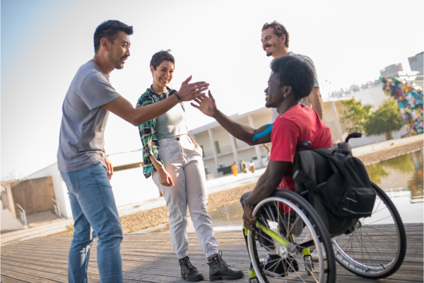 A young man in a wheelchair shaking hands with a standing individual, representing inclusivity in NDIS Respite Accommodation Melbourne by Lifecare Independent Living.