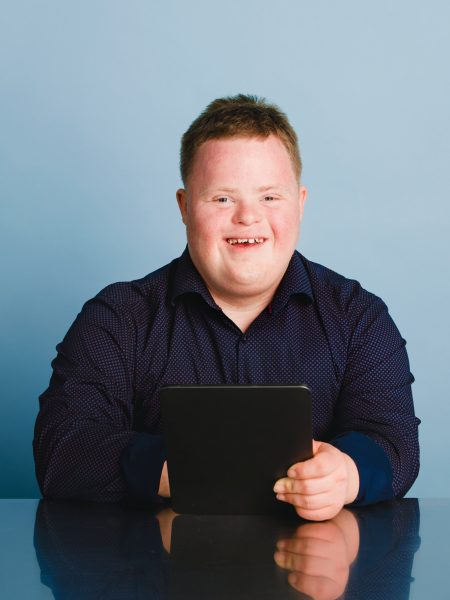 Cute boy with down syndrome homeschooling using a digital tablet during the coronavirus pandemic