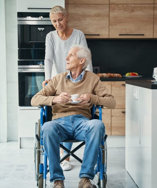 Pleased aged woman supporting her disabled husband